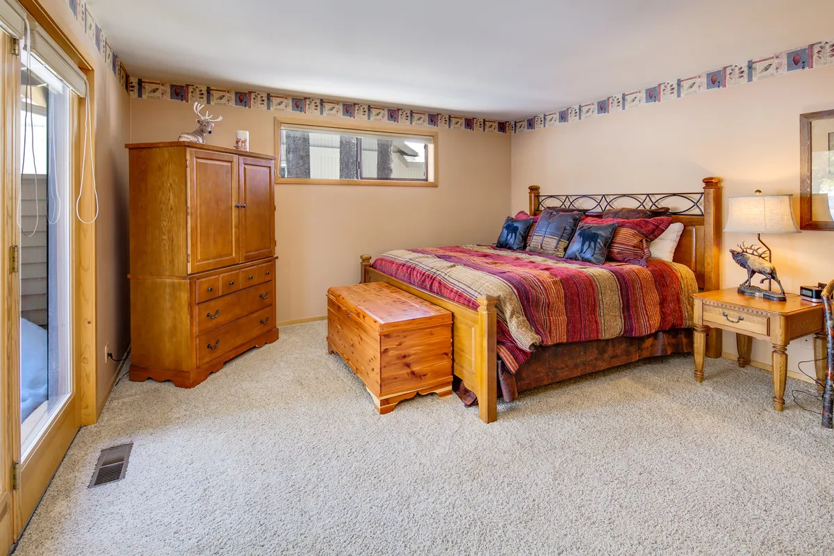 A cozy bedroom with a bed adorned in colorful bedding, a wooden storage chest at the foot, and a dresser. The room is inviting, filled with warm light, and exudes a sense of comfort perfect for reading or relaxing after a day spent exploring.