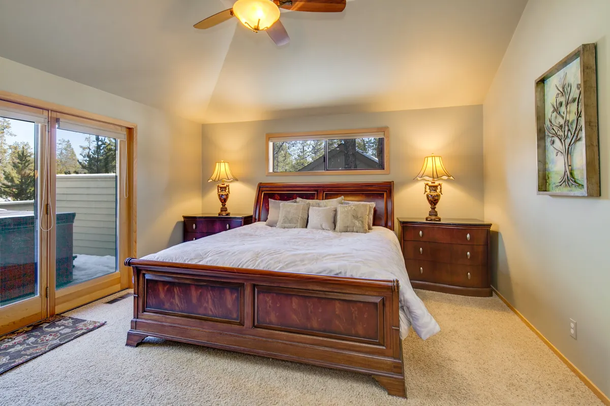 A tranquil bedroom featuring a king-sized bed with plush bedding, a wooden dresser, and two bedside lamps. Natural light streams through the window, creating a serene and restful atmosphere. The space feels private and thoughtfully appointed, ideal for relaxation and personal downtime.