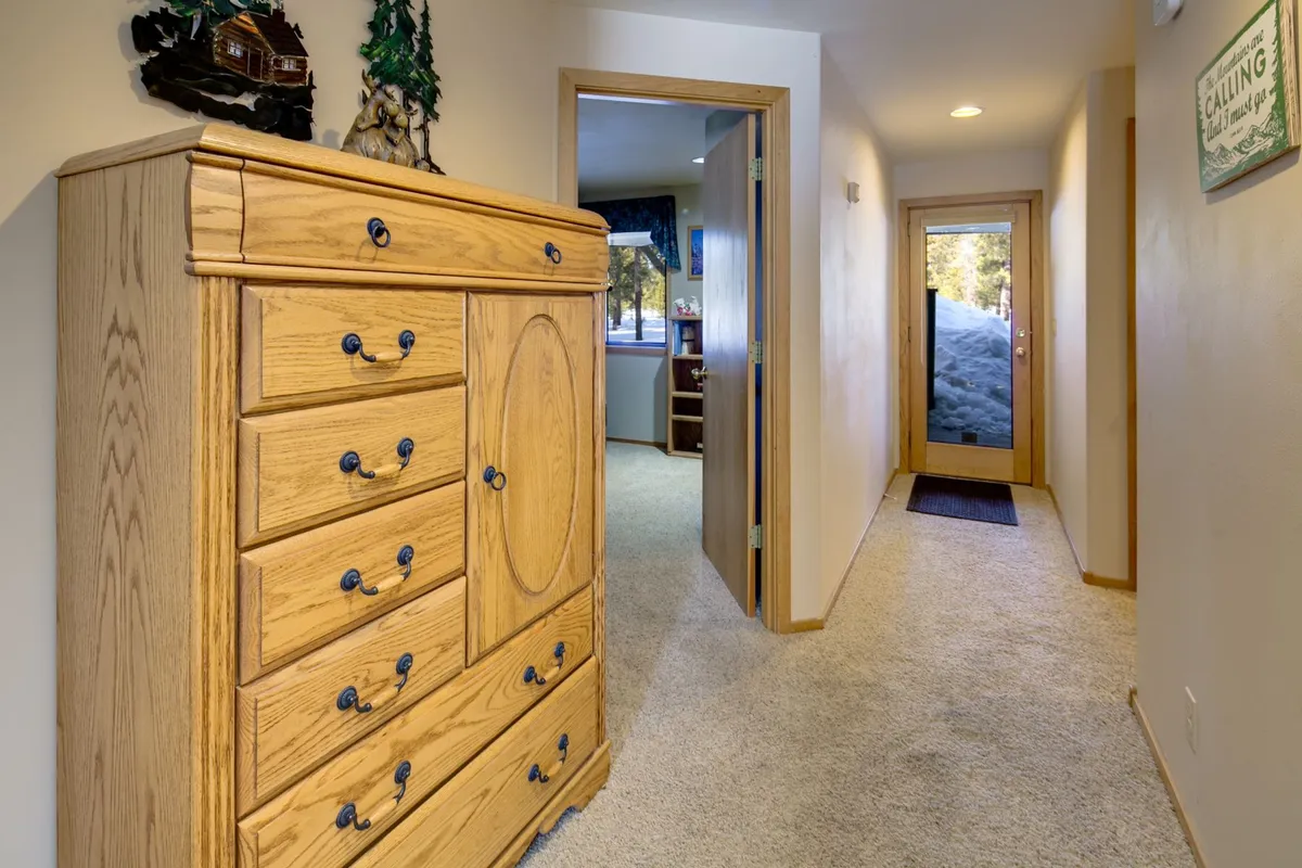 This image presents the entryway of the home with a view of a wooden dresser, an open doorway leading to another room, and the front door with a window that allows natural light to stream inside. The setup hints at welcoming guests and coming and going—connecting the inside ambiance with the idea of venturing out to Sunriver's recreation amenities.