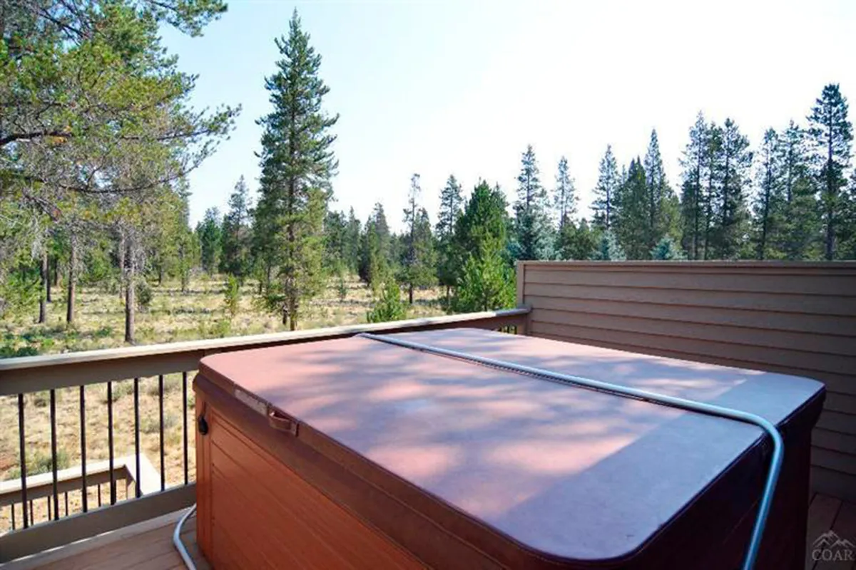 This image highlights the hot tub nestled on the deck, surrounded by pine trees and a rustic railing. The scene exudes tranquility, perfect for soaking while watching sunsets, stargazing, or enjoying peaceful mornings immersed in nature.